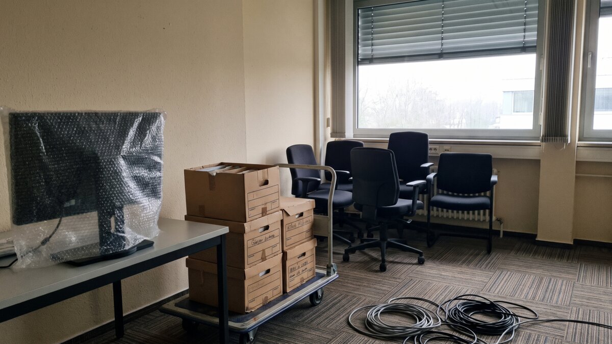 Verpackter Monitor und beschriftete Aktenkartons auf einem Rollwagen