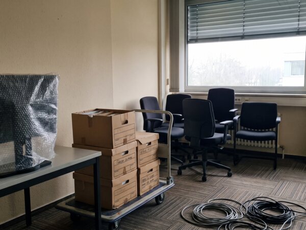 Verpackter Monitor und beschriftete Aktenkartons auf einem Rollwagen