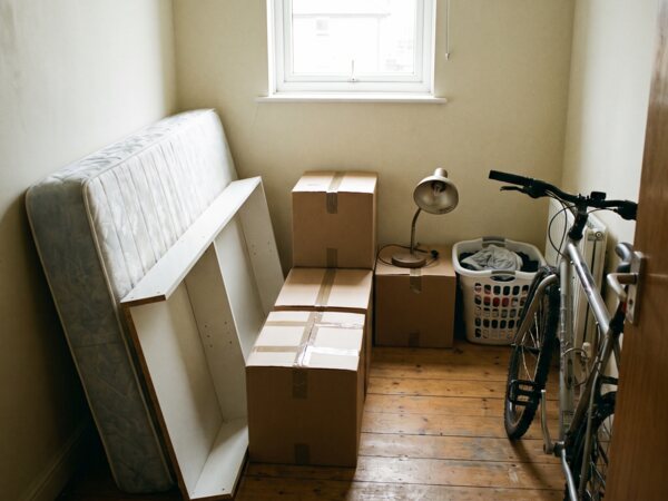 Kleines Zimmer mit Matratze, Kartons und Fahrrad beim Auszug