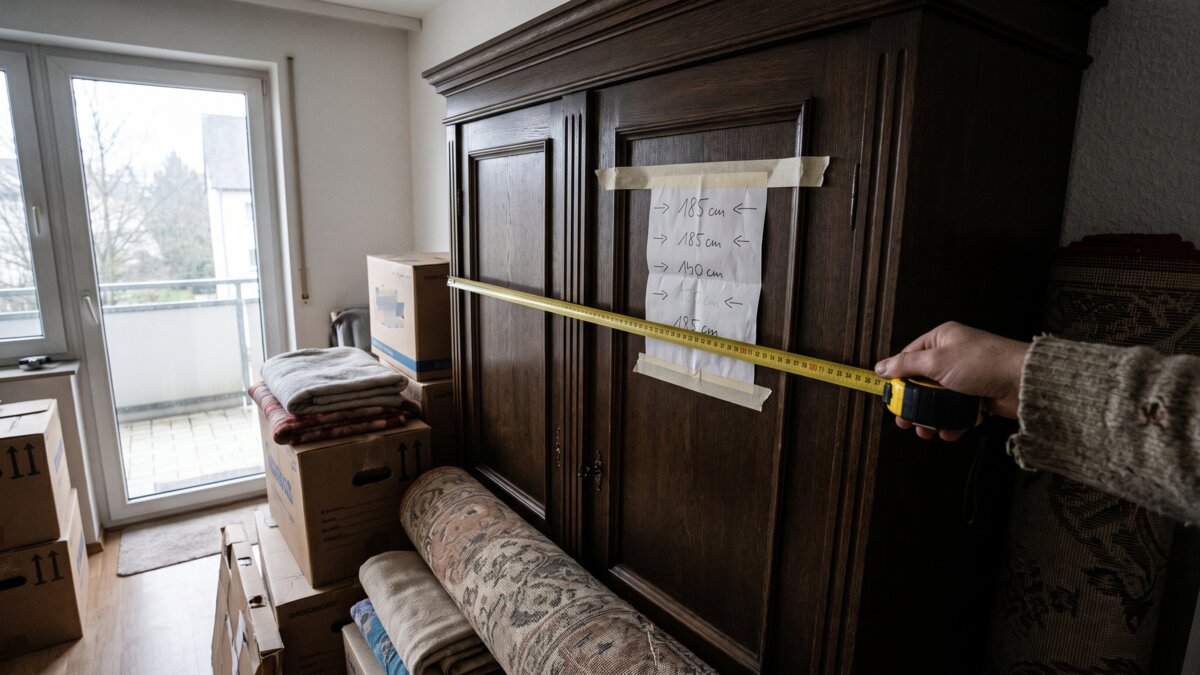 Schrank wird vor dem Umzug mit einem Maßband ausgemessen