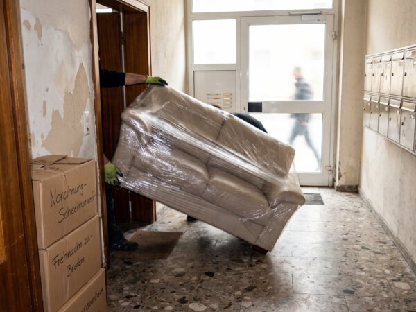 Eingepacktes Sofa wird durch einen Hausflur getragen
